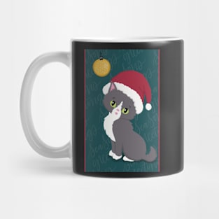 Cute Christmas card with a little kitten in a Christmas hat looking at a bauble. Mug